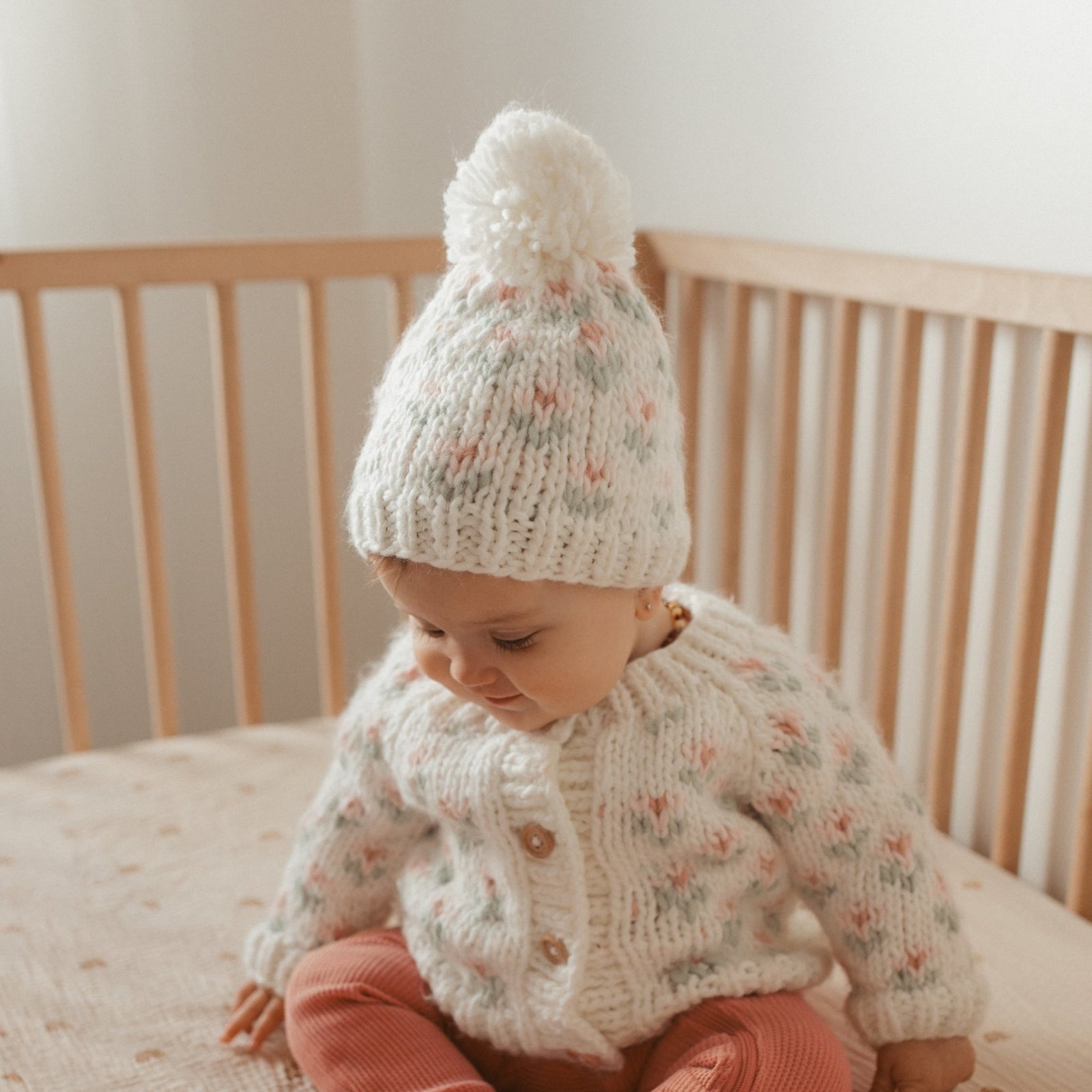Baby girl wearing white hand knit floral cardigan by Huggalugs