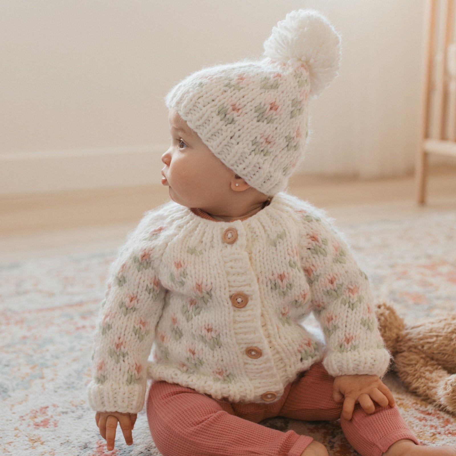 Baby girl wearing white hand knit floral cardigan by Huggalugs